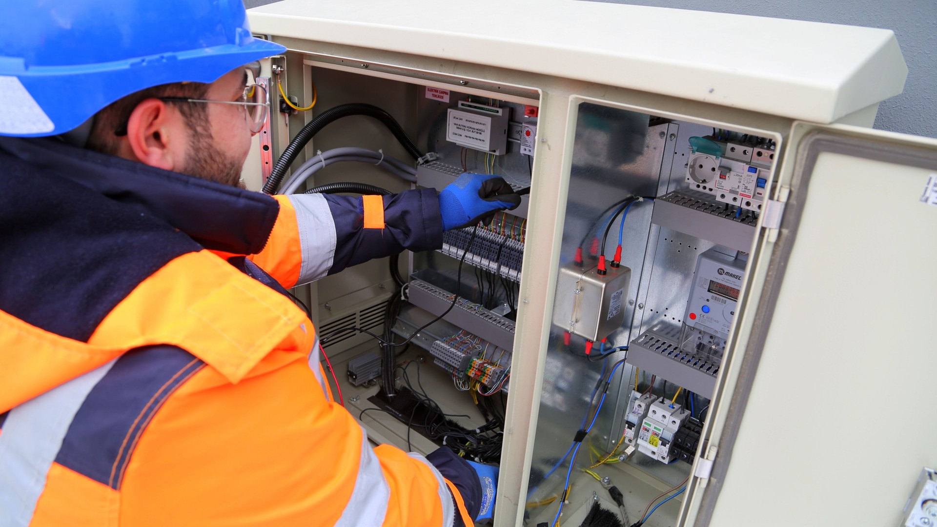 Eletricista com equipamento de proteção trabalhando em quadro elétrico, ilustrando o serviço da WG Instalações Elétricas